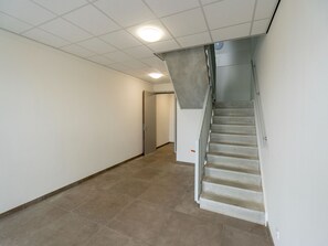 En gang med tæppe, en trappe med gelænder og en dør for enden.