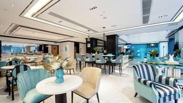 A modern hotel lobby with seating areas, a bar, and a view of the city.