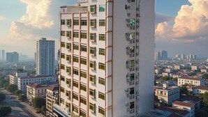 Un immeuble de grande hauteur, doté de nombreux étages, de climatiseurs installés à l’extérieur et offrant une vue sur le paysage urbain en arrière-plan.