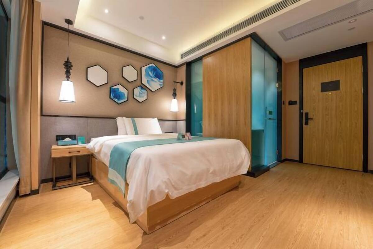 A modern hotel room with a large bed, bedside tables, a wardrobe, and a wall with geometric art.