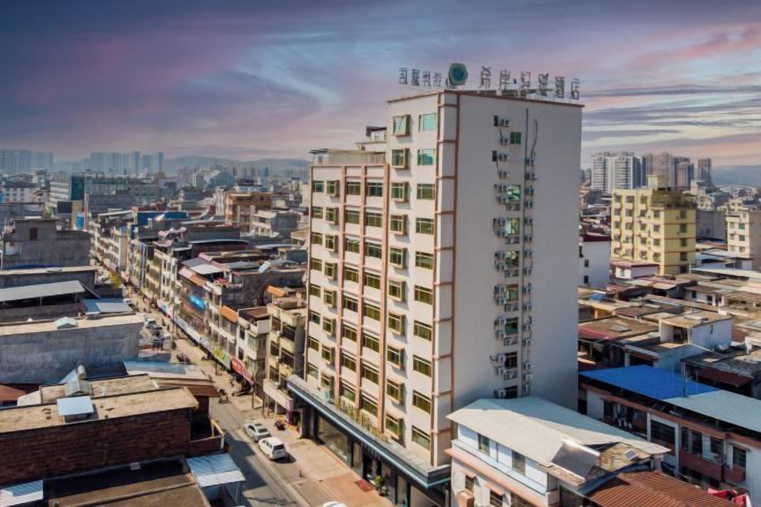 A multi-story building with a flat roof, surrounded by other buildings, and a clear sky in the background.