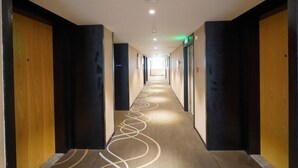 Un couloir d'hôtel avec un sol recouvert de moquette et des portes de part et d'autre.