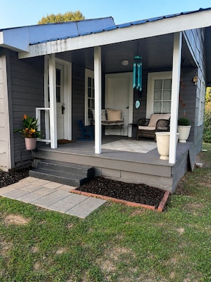 A covered porch with a seating area, a potted plant, and a hanging light fixture.