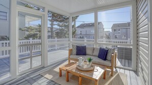 A sunlit room with a wooden deck, a sofa with cushions, and a coffee table with a tray. - Sunshine and Bethany Beach Dreams (Bethany Beach)