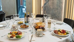 A breakfast setting with multiple plates of food, wine glasses, and coffee cups on a table. - HOTEL DUNAREA MAMAIA (Constanta)