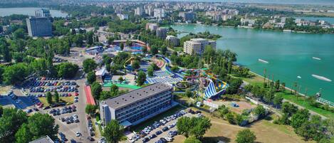 Une vue aérienne d’une ville avec un grand parc, une étendue d’eau et un parking.
