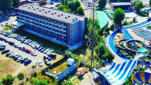 An aerial view of a hotel with multiple floors, a parking lot, and a water park with slides and pools. - HOTEL DUNAREA MAMAIA (Constanta)