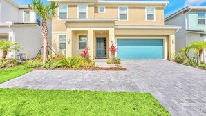 A two-story house with a garage, a well-maintained lawn, and a variety of plants.