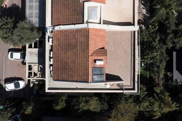 An aerial view of a house with a distinct L-shaped layout, a small attached garage, and a visible window.