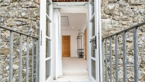 A stone building entrance with a wooden door, a metal railing, and a carpeted staircase. - Hideout by Stay Lagom (Ballycastle)