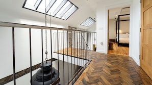 A modern interior with a wooden herringbone floor, a metal railing, and skylights. - Hideout by Stay Lagom (Ballycastle)