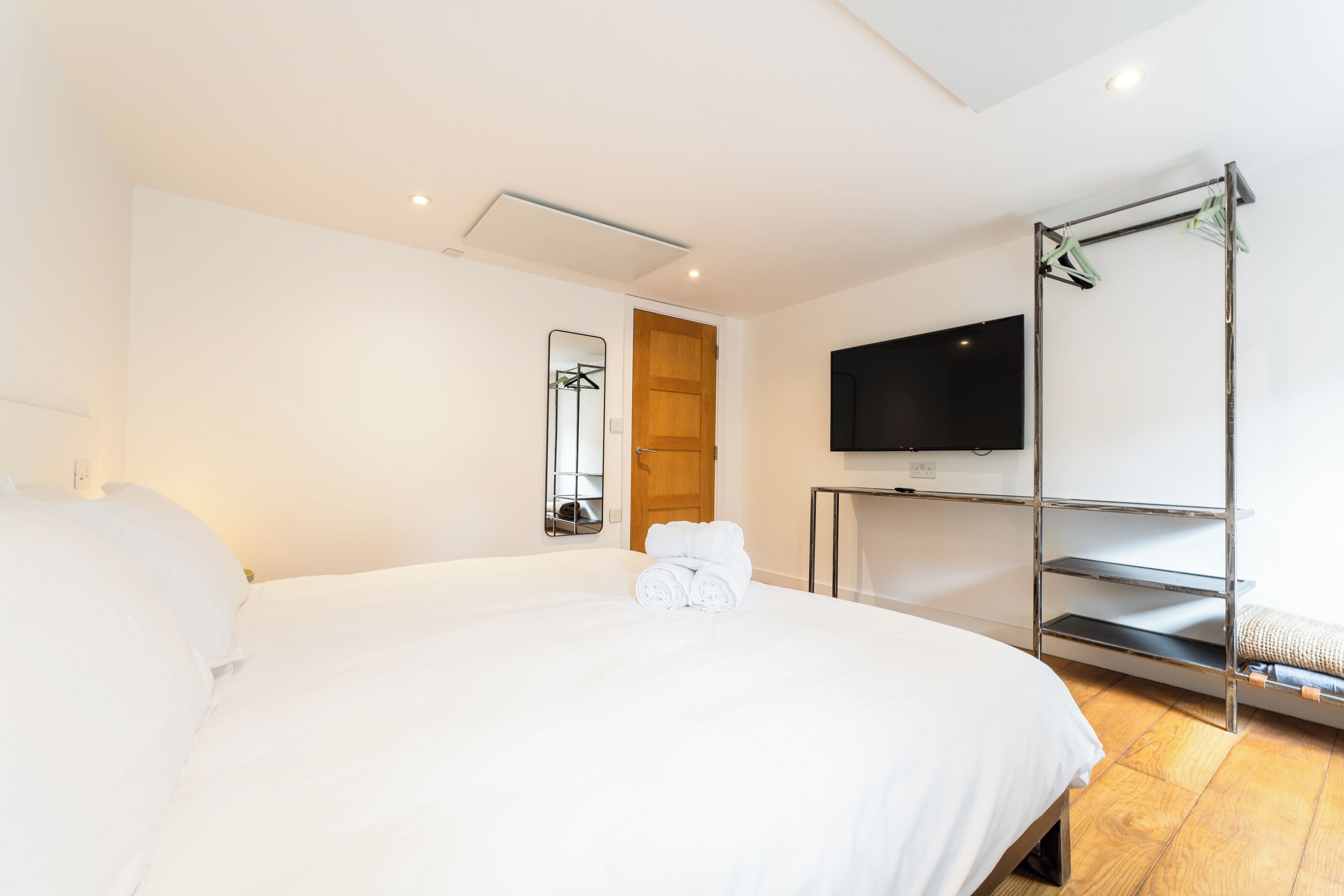 Una habitación de hotel con una cama grande, un televisor montado en la pared y una puerta de madera.