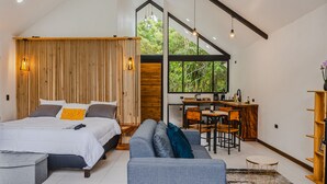 Een moderne slaapkamer met een bed, een bank, een bureau en een eethoek.