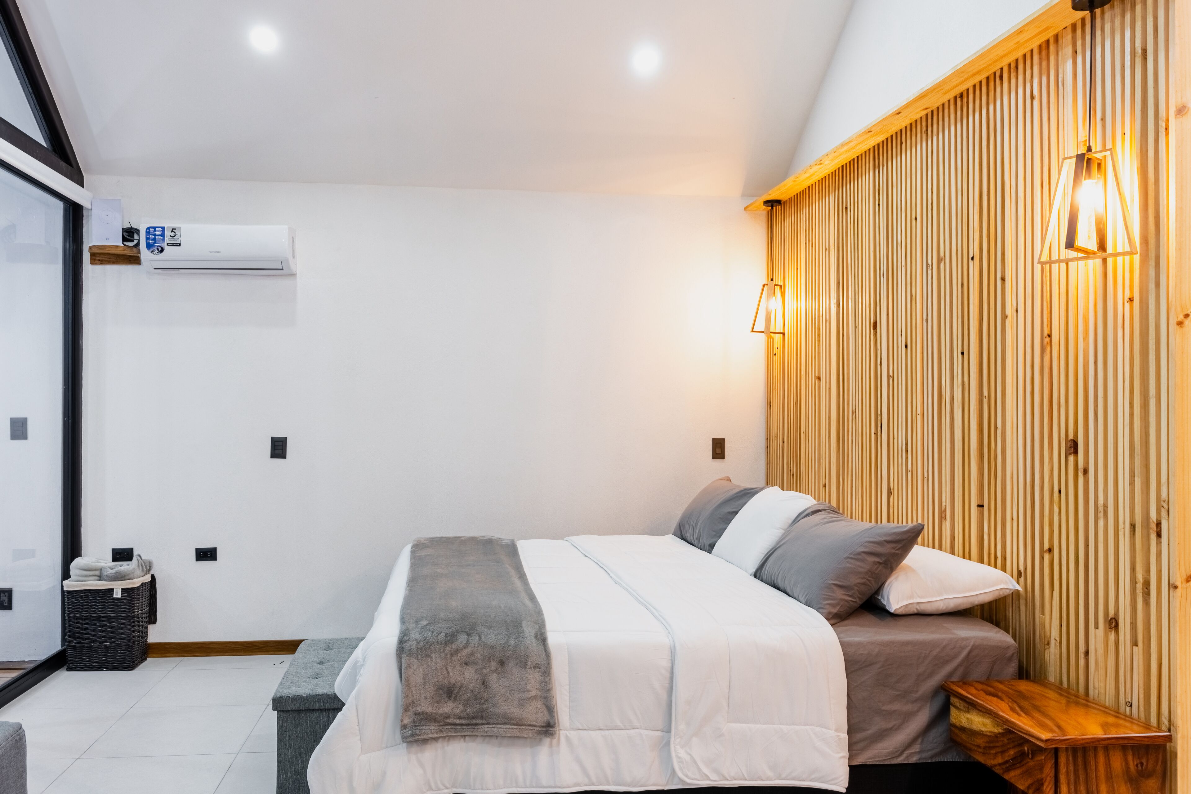A modern bedroom with a bed, bedside table, and a wooden slat wall.