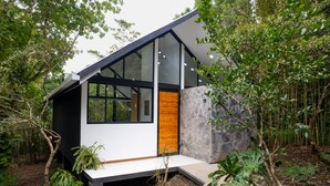 Een modern huis met een groot raam, een stenen muur en een houten deur.