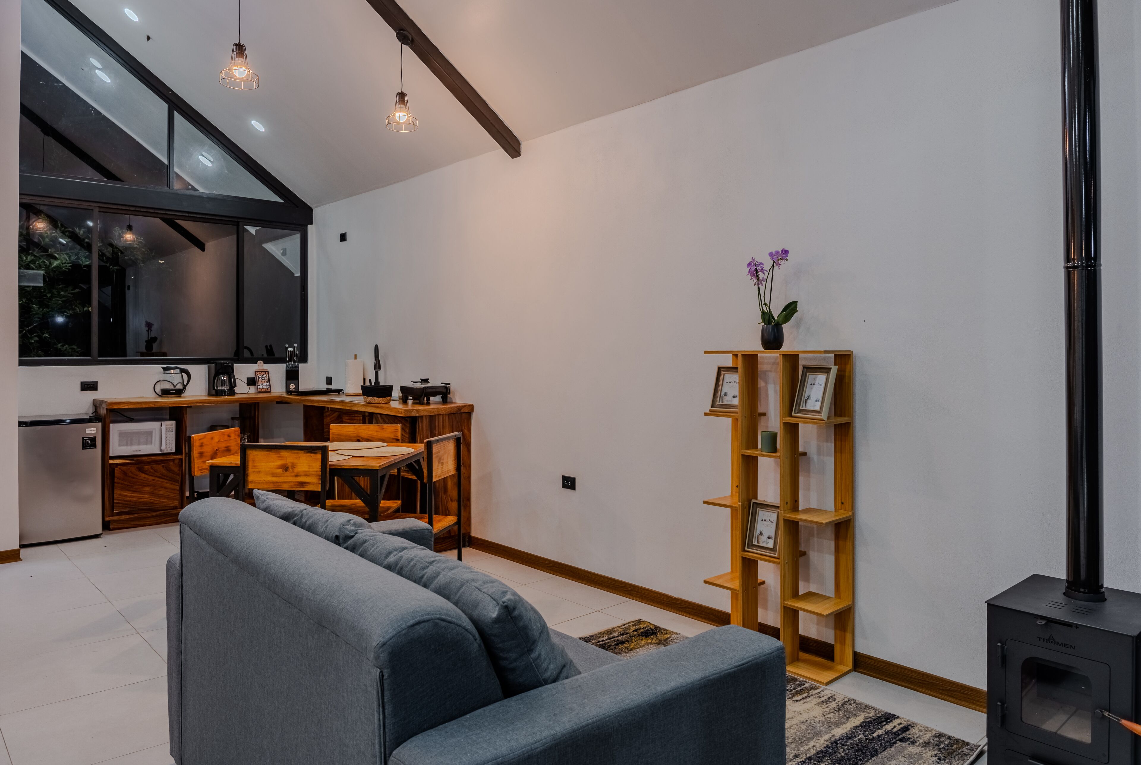 A modern living room with a sofa, dining table, and kitchen area.