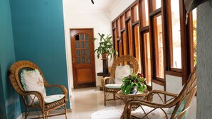 A room with two wicker chairs, a wooden door, and a potted plant. - Recanto da Rose Guesthouse (Caraguatatuba)