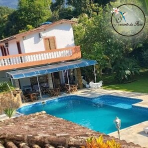 A two-story house with a swimming pool, outdoor furniture, and a garden. - Recanto da Rose Guesthouse (Caraguatatuba)