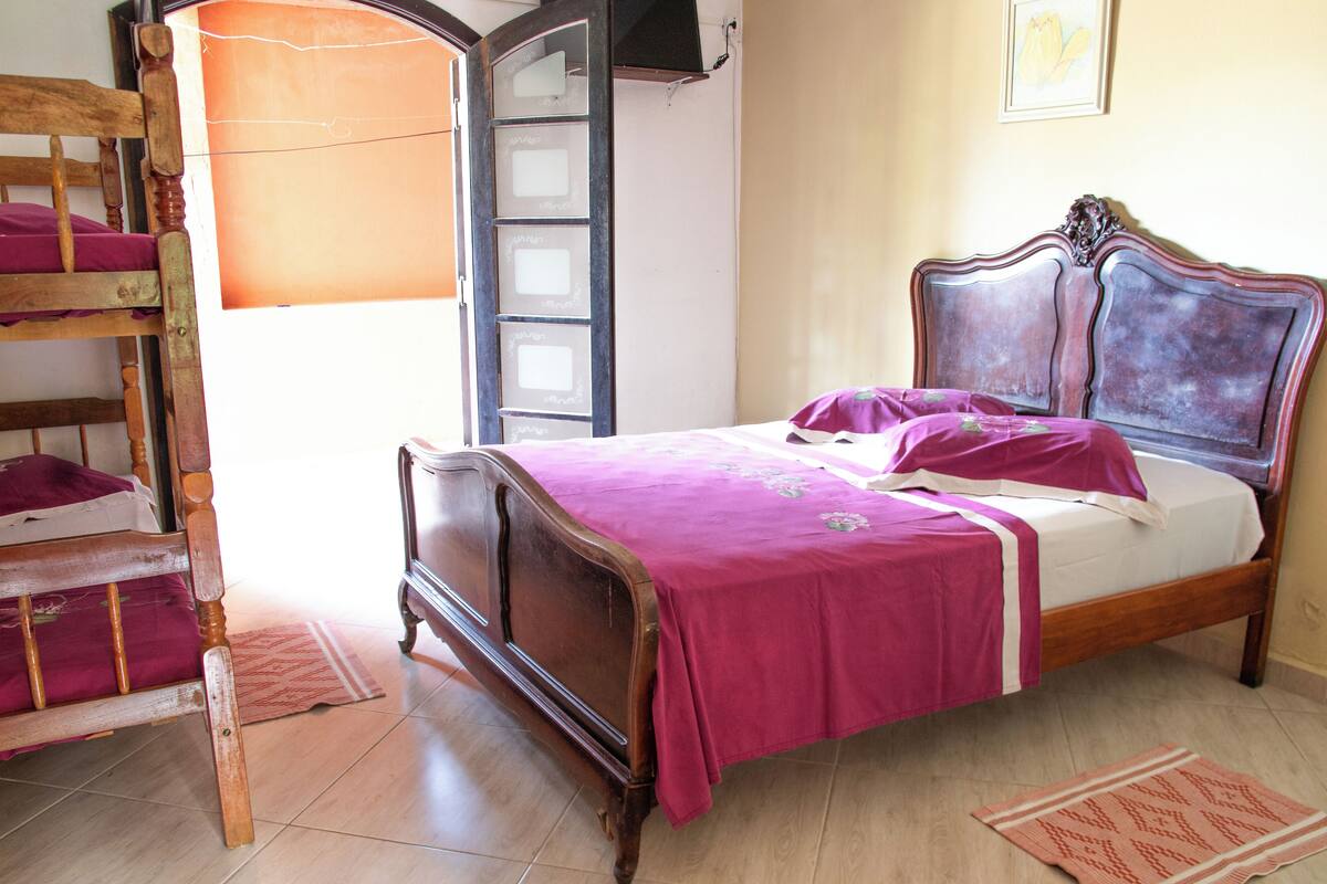 Une chambre avec un lit en bois, une chaise en bois, une armoire et une fenêtre.