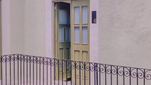 Un edificio con una puerta color crema, una placa con un número y una barandilla de metal.