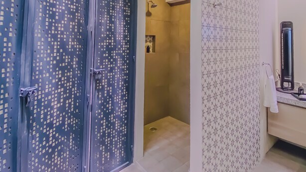 Un baño moderno con ducha, pared con diseño y techo con plantas colgantes.