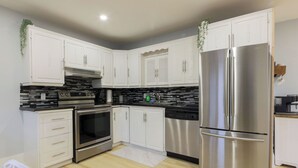 Una cocina moderna con armarios blancos, electrodomésticos de acero inoxidable y un salpicadero de encimera negro.