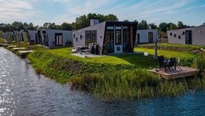 A modern waterfront property with multiple cabins, a dock, and a grassy area. - Modern Chalet 5 km From Kampen (Kampen)