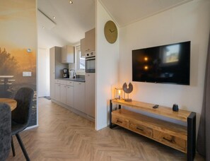 Eine moderne Küche mit Flachbildfernseher, einer Holzbank und einer Wanduhr.