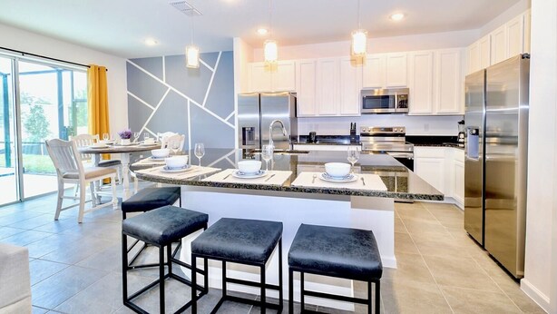 A modern kitchen with white cabinets, stainless steel appliances, and a central island with bar stools.