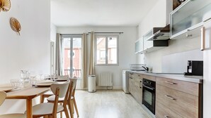 Cocina moderna con comedor, que incluye una mesa de madera, sillas y un horno empotrado.