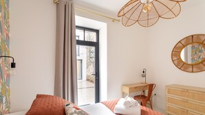 Une chambre à coucher avec un lit, une commode, un bureau et une fenêtre avec des rideaux.
