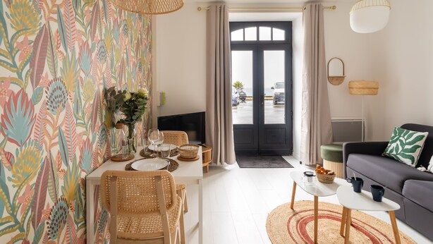Un salon moderne avec un coin repas, comprenant une grande fenêtre, un canapé, un téléviseur et un mur décoratif.