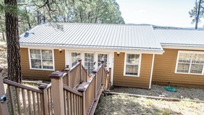 A two-story house with a metal roof, wooden deck, and a small garden area. - Cozy 2-bedroom cabin in lovely Ruidoso (Ruidoso)