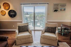 A living room with two armchairs, a coffee table, and a view through a sliding glass door to a balcony.