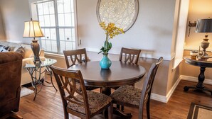 A dining area with a round table, four chairs, a vase with yellow flowers, and a decorative wall piece. - Cozy 2-bedroom cabin in lovely Ruidoso (Ruidoso)
