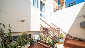 A small outdoor area with potted plants, a wooden fence, and a water spout.