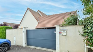 Ett bostadsområde med stängda grindar, ett garage med stängd port, en blå bil parkerad framför och en skylt som visar fastighetens namn.