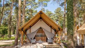 Eine rustikale Holzhütte mit Satteldach, Steinstufen, die zu einer Holzterrasse führen, und einem überdachten Sitzbereich mit Stühlen und Tisch.