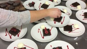 A kitchen with multiple plates of desserts, including chocolate pieces and ice cream, arranged on a stainless steel counter.