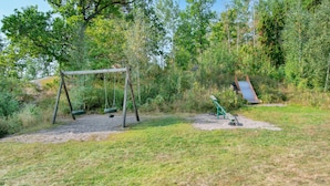 A playground with a swing set and a slide, surrounded by trees and grass. - Pet friendly home in Mariefred with WiFi (Mariefred)