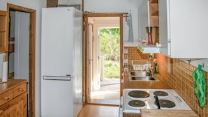A compact kitchen with a white refrigerator, wooden cabinets, a sink, and a stove. - Pet friendly home in Mariefred with WiFi (Mariefred)