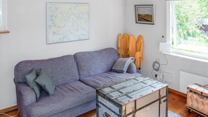 A room with a purple sofa, a map on the wall, and a window with a view of greenery. - Pet friendly home in Mariefred with WiFi (Mariefred)
