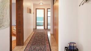 A hallway with a wooden door, a patterned rug, and a map on the wall. - Ferienwohnung mit Balkon im Schwarzwald (Waldachtal)