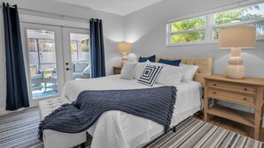 Un dormitorio con cama, mesitas de noche, una ventana y vistas al exterior.