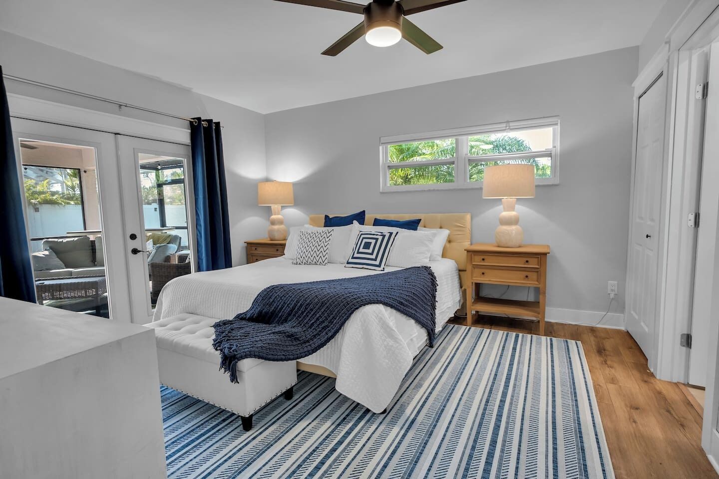A bedroom with a bed, nightstands, a ceiling fan, and a window.