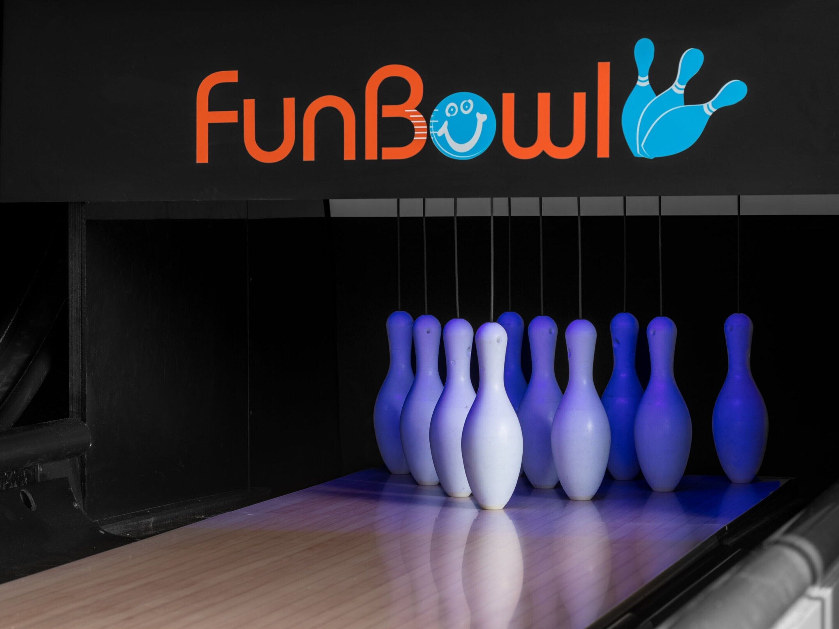 En bowlinghal med et skilt, der siger "FunBowl", og en række blå bowlingkegler.