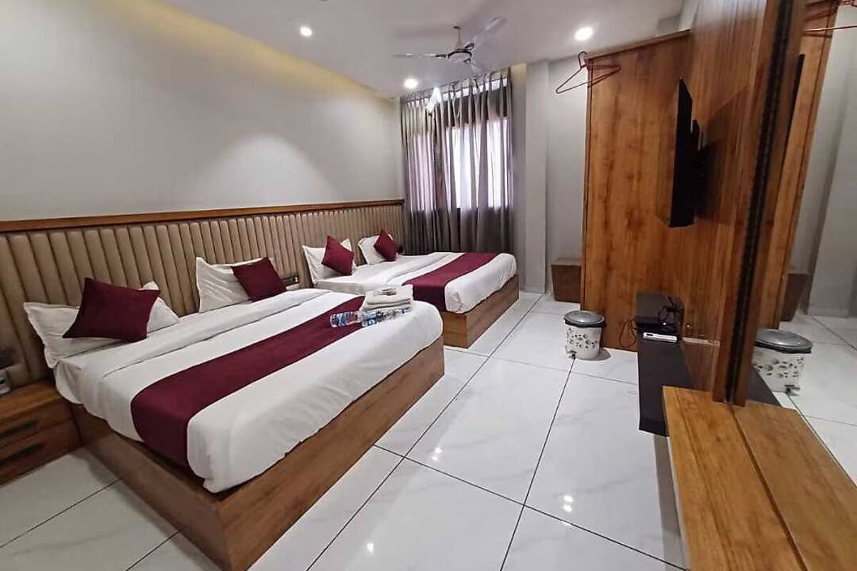 A hotel room with two beds, a wooden wardrobe, a TV, and a ceiling fan.