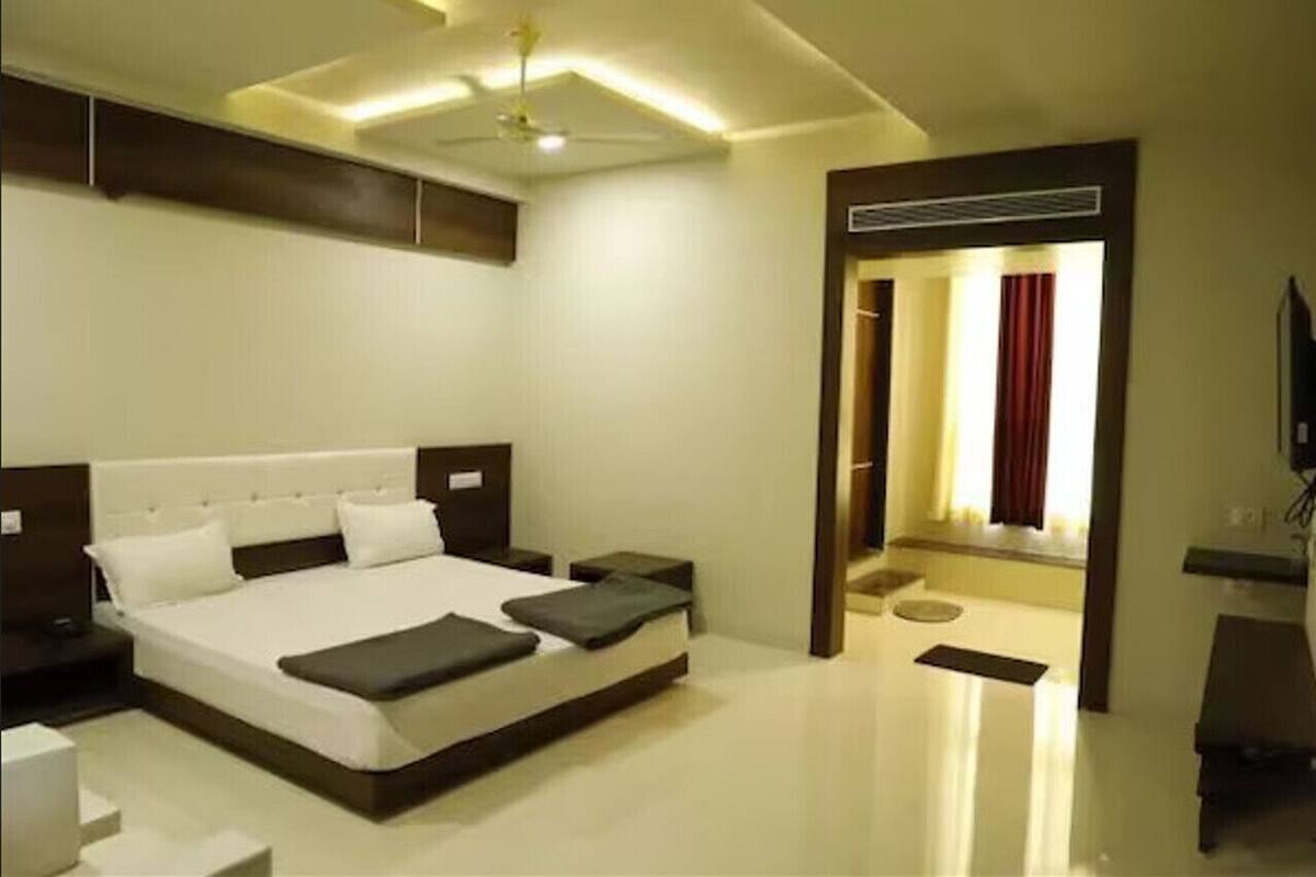 A modern hotel room with a large bed, bedside tables, a flat-screen TV, and a ceiling fan.