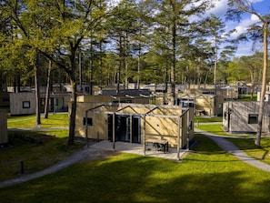 A campsite with multiple cabins, each with a door and windows, surrounded by trees. - Safari Tent in Eindhoven Near Nature Park (Mierlo)
