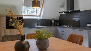 A modern kitchen with a skylight, a dining table with two vases, and a built-in oven.
